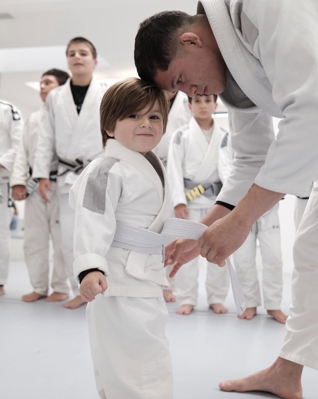 Gabriel Luz helping a young student with their Jiu-Jitsu belt