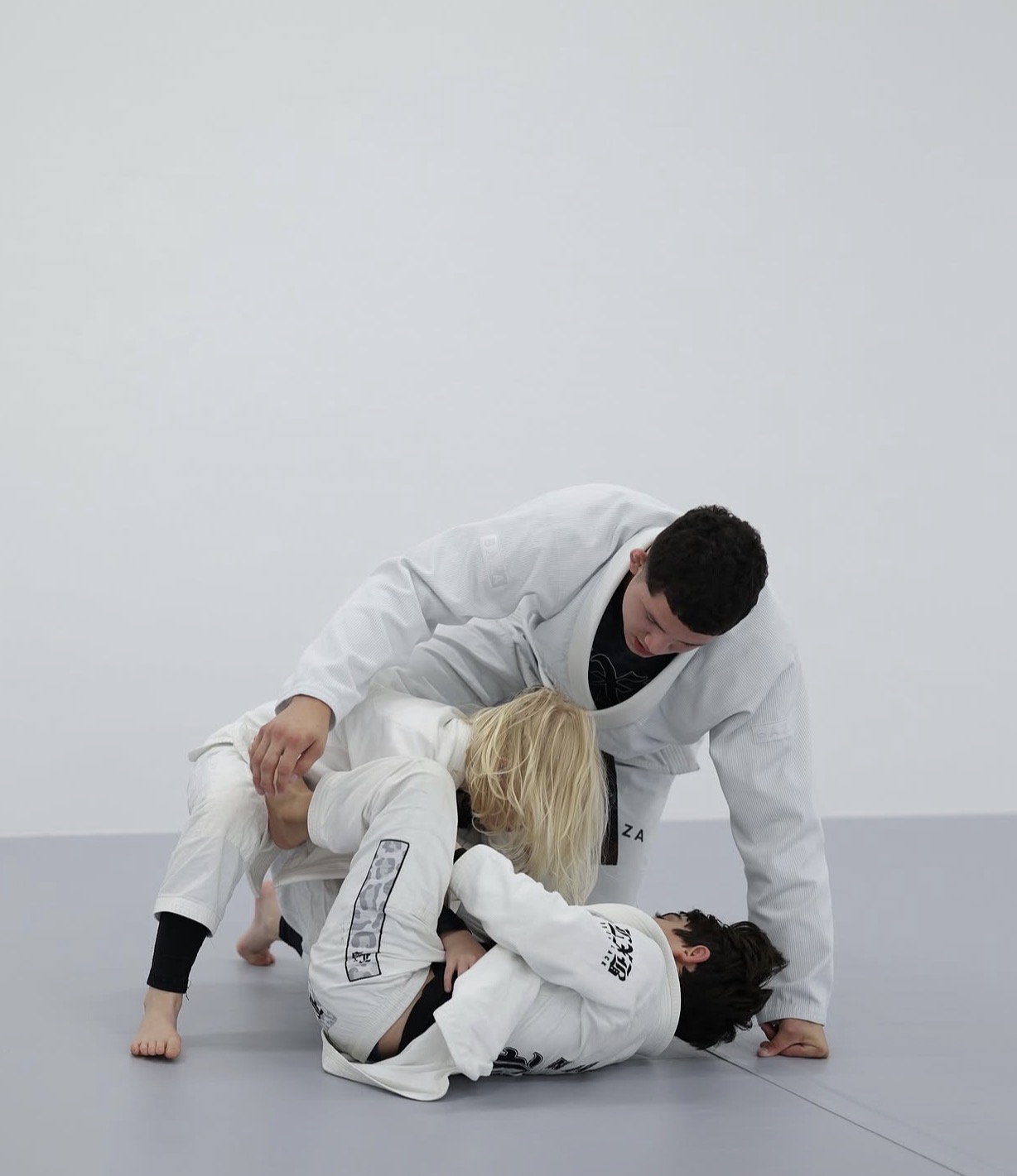Gabriel Luz guiding two young students during Jiu-Jitsu practice